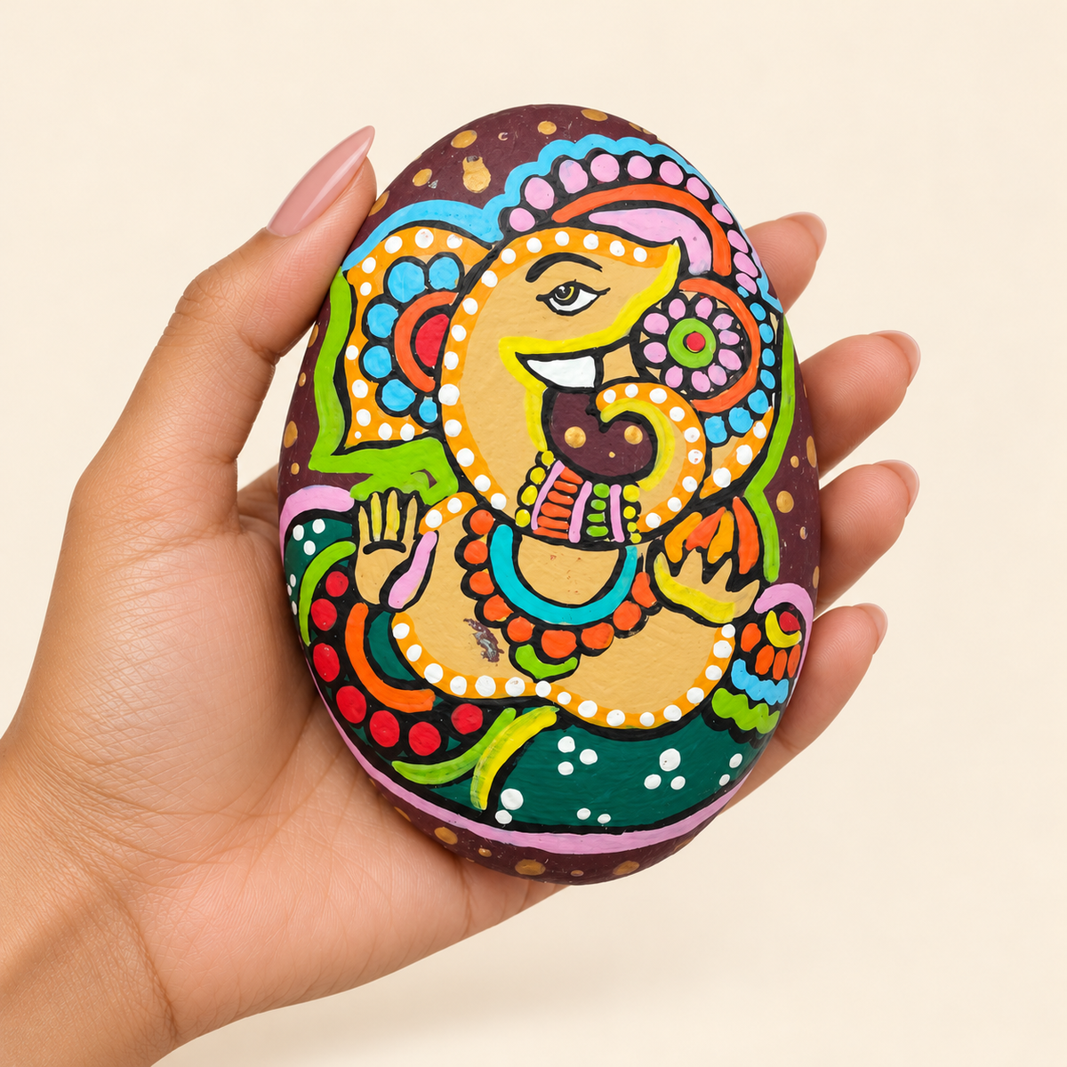 Ganesh: Harvest Blessing hand-painted natural pebble art, shown in hand for scale