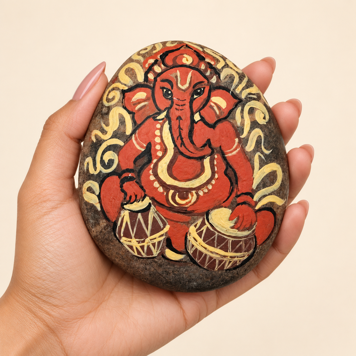 Ganesh: Rhythm of Blessings hand-painted natural pebble art, shown in hand for scale