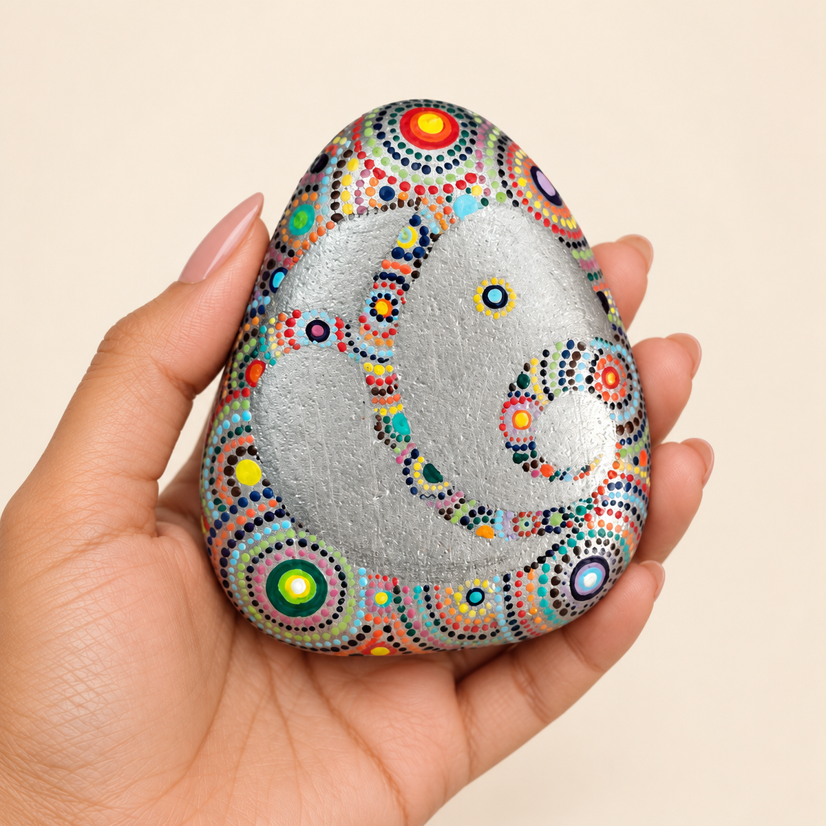 Ganesh: Silver Mandala hand-painted natural pebble art, shown in hand for scale