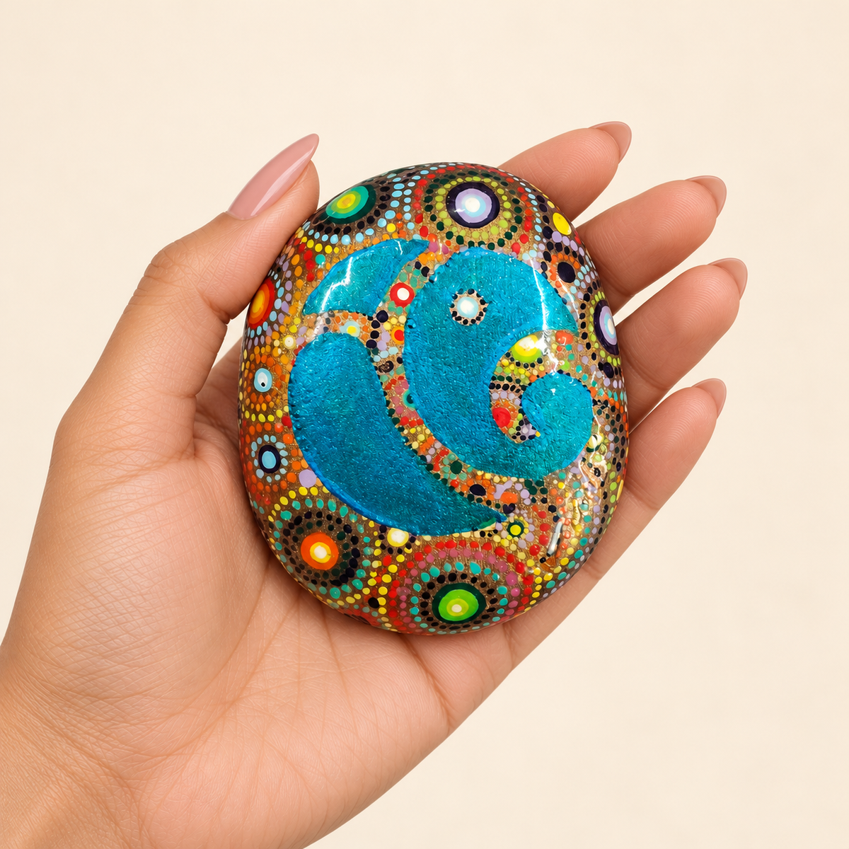 Ganesh: Peacock Jewel hand-painted natural pebble art, shown in hand for scale