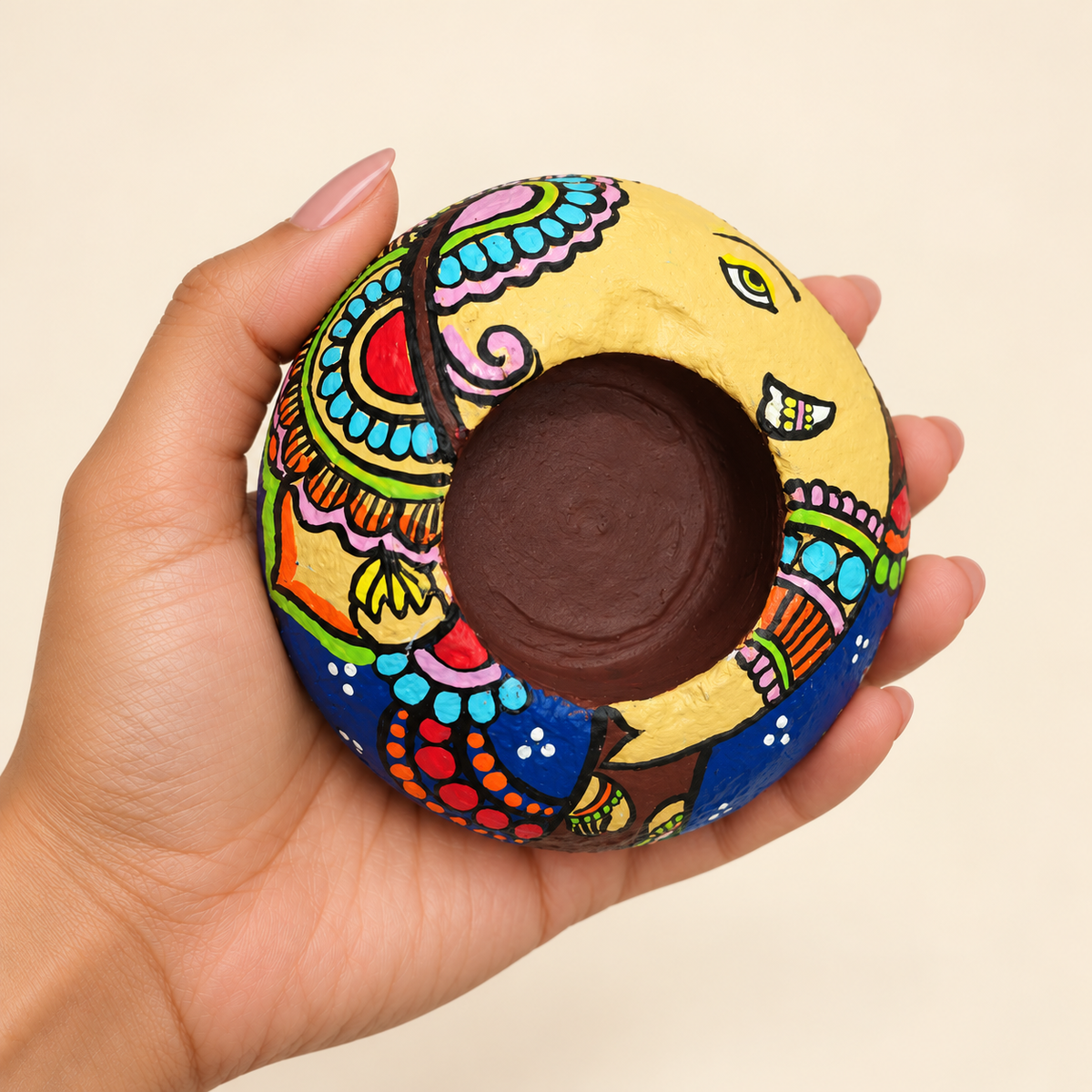 Ganesh: Joyful Offering hand-painted natural pebble tealight holder, shown in hand for scale