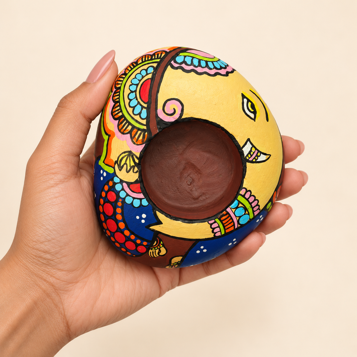 Ganesh: Auspicious Colours hand-painted natural pebble tealight holder, shown in hand for scale