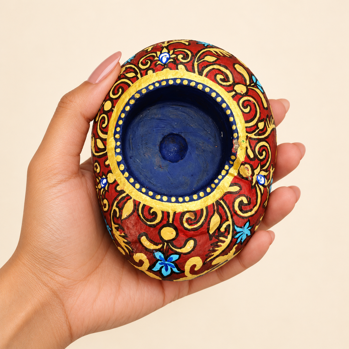Royal Scroll: Sapphire Glow hand-painted natural pebble tealight holder, shown in hand for scale