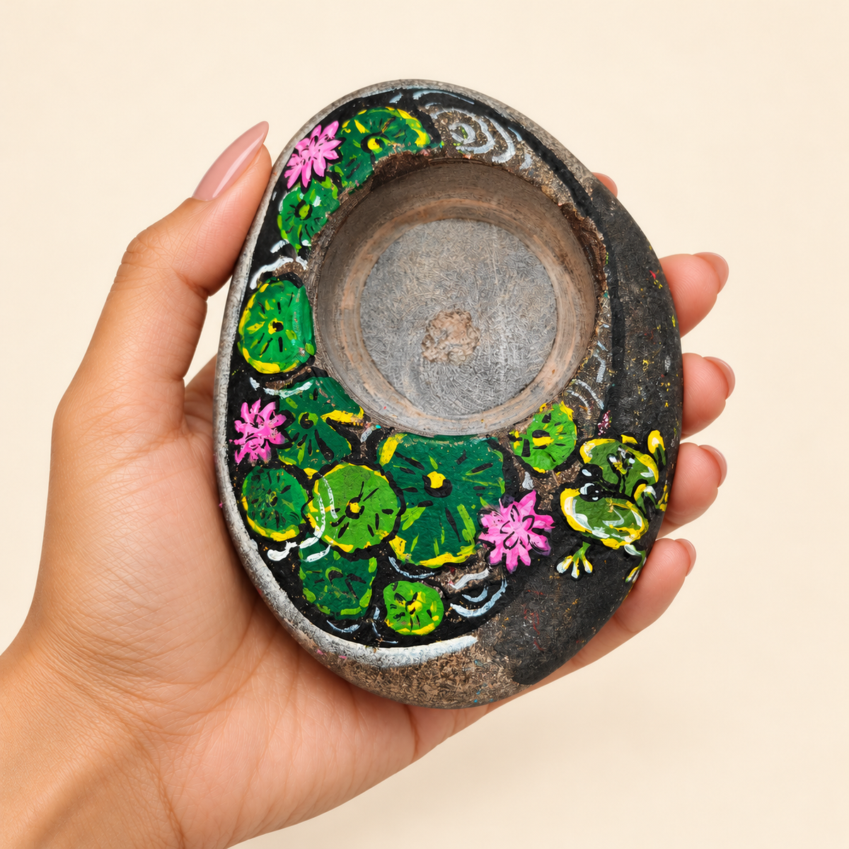 Lotus Pond: Midnight Garden hand-painted natural pebble tealight holder, shown in hand for scale