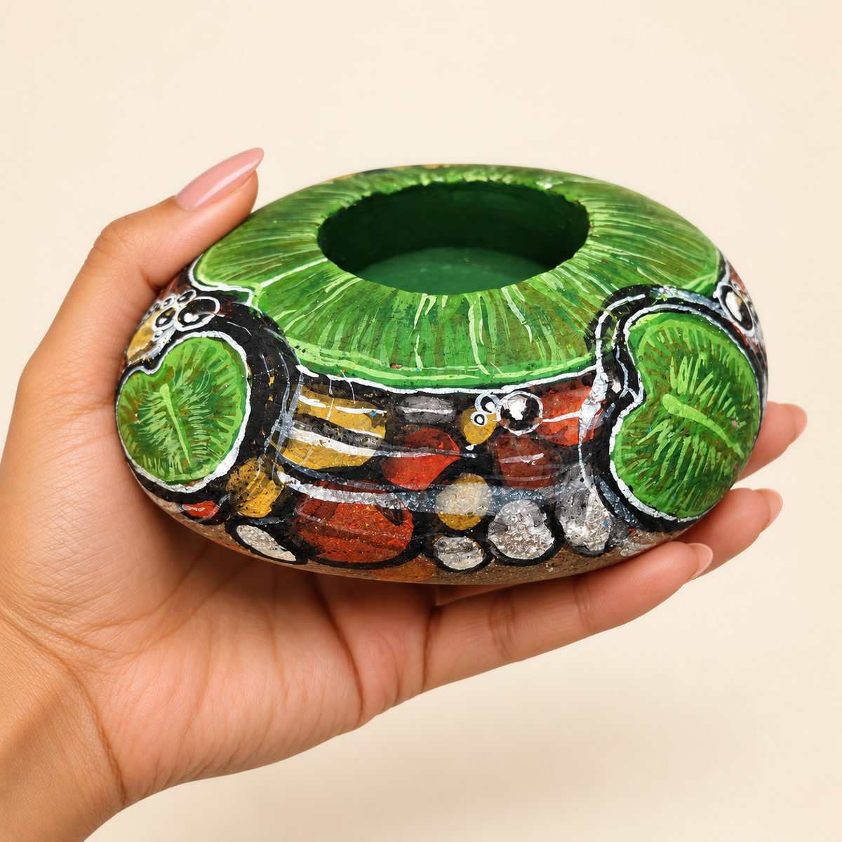 Forest Lotus: Emerald Stillness hand-painted natural pebble tealight holder, shown in hand for scale