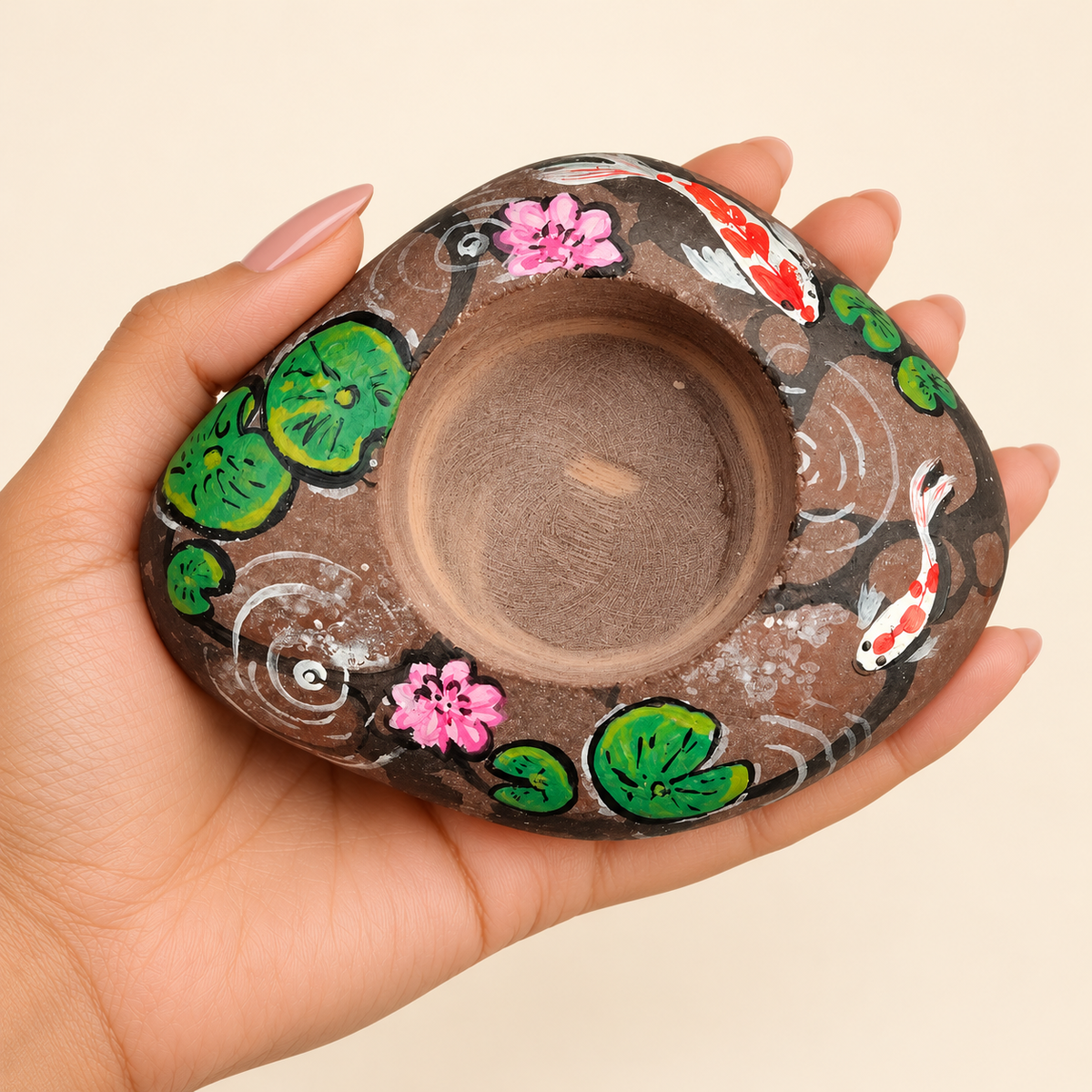 Lotus Pond: Koi Garden hand-painted natural pebble tealight holder, shown in hand for scale