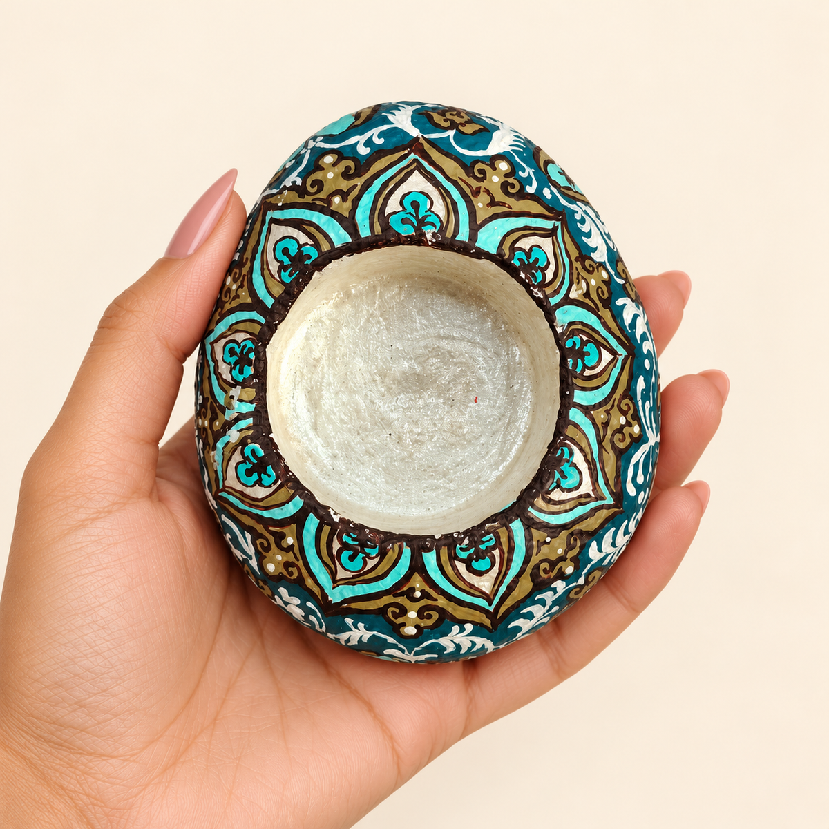 Turquoise Arabesque: Pearl Glow hand-painted natural pebble tealight holder, shown in hand for scale