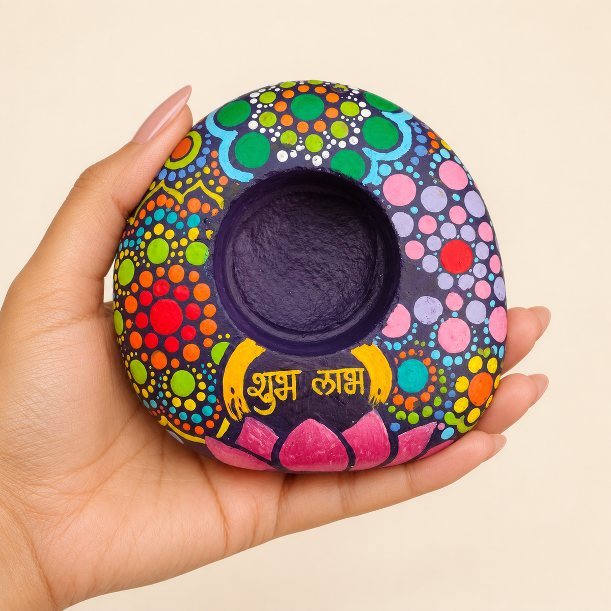 Shubh Labh: Kaleidoscope Bloom hand-painted natural pebble tealight holder, shown in hand for scale