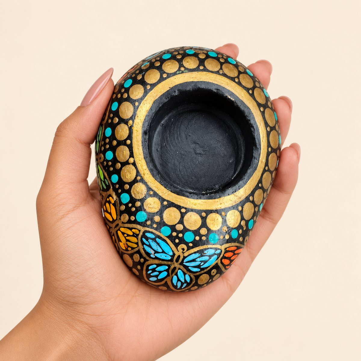 Butterfly Garden: Golden Night hand-painted natural pebble tealight holder, shown in hand for scale