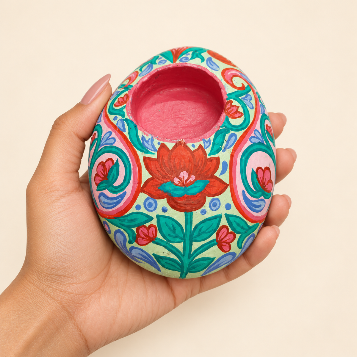 Turquoise Lotus: Coral Bloom hand-painted natural pebble tealight holder, shown in hand for scale