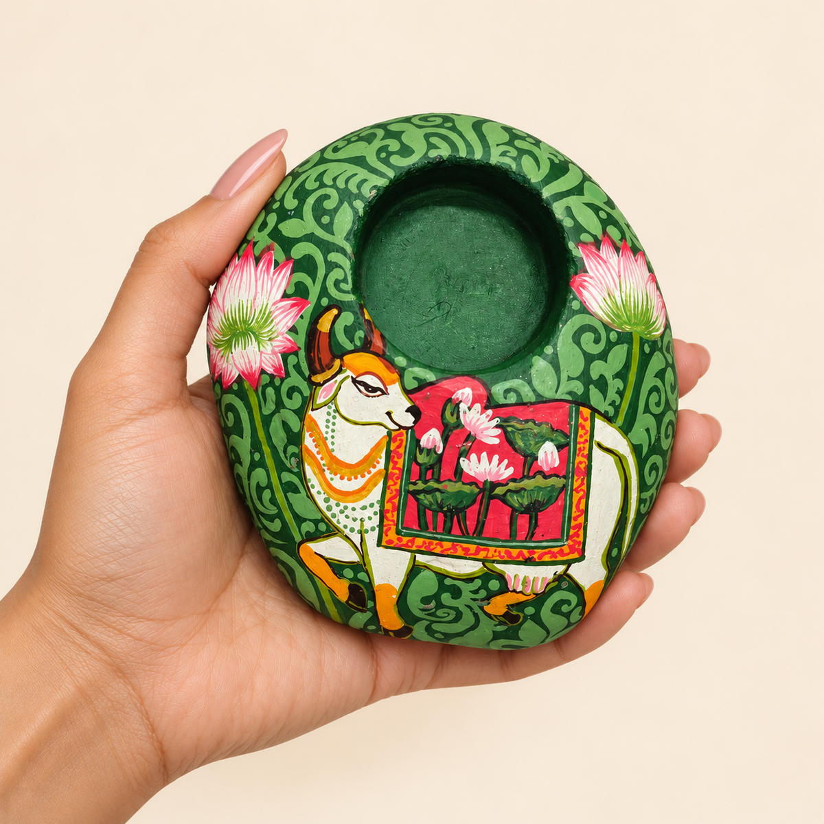 Kamdhenu: Emerald Garden hand-painted natural pebble tealight holder, shown in hand for scale