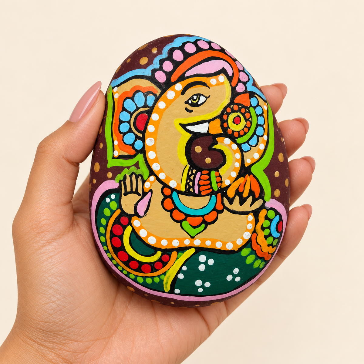 Ganesh: Verdant Celebration hand-painted natural pebble art, shown in hand for scale