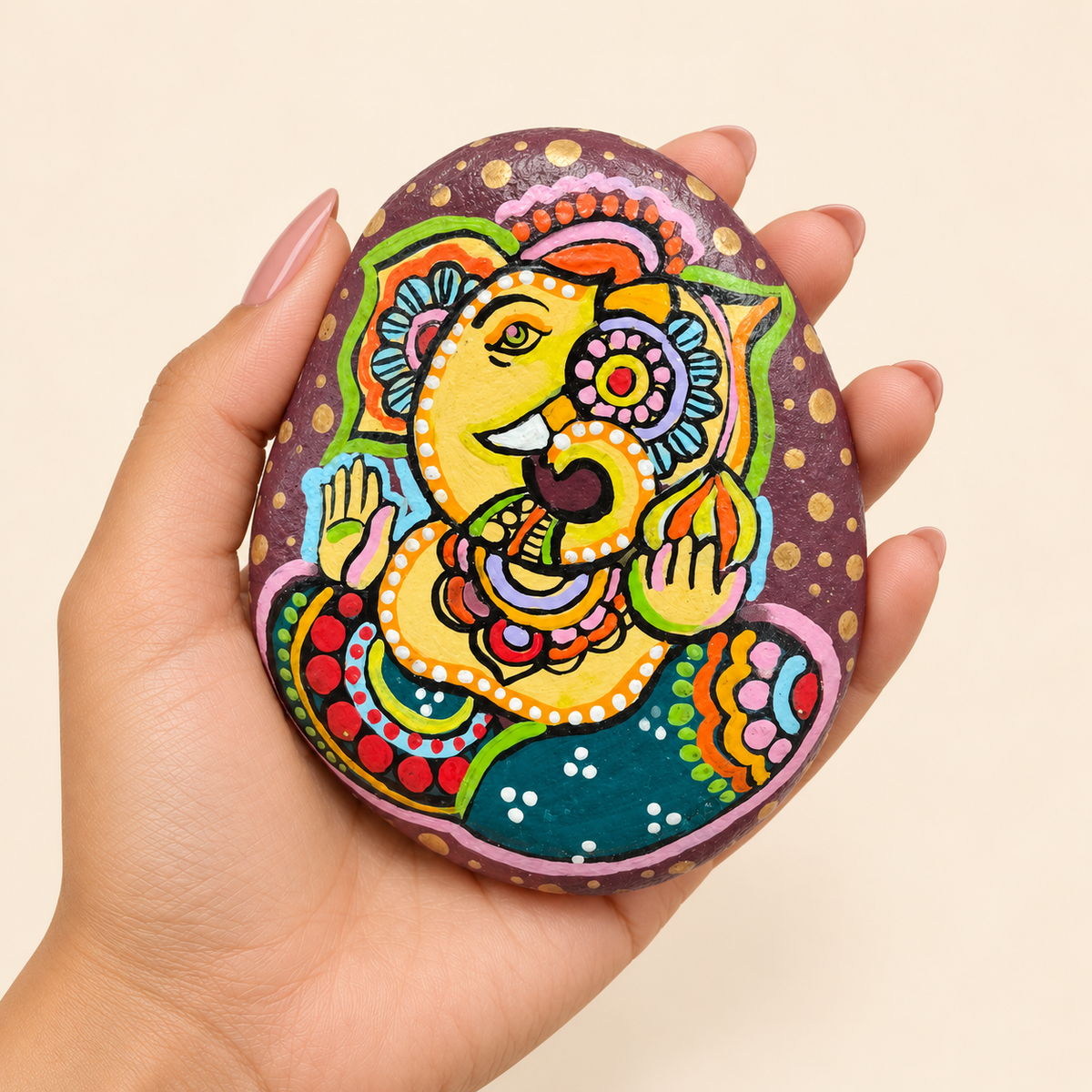 Ganesh: Floral Abundance hand-painted natural pebble art, shown in hand for scale