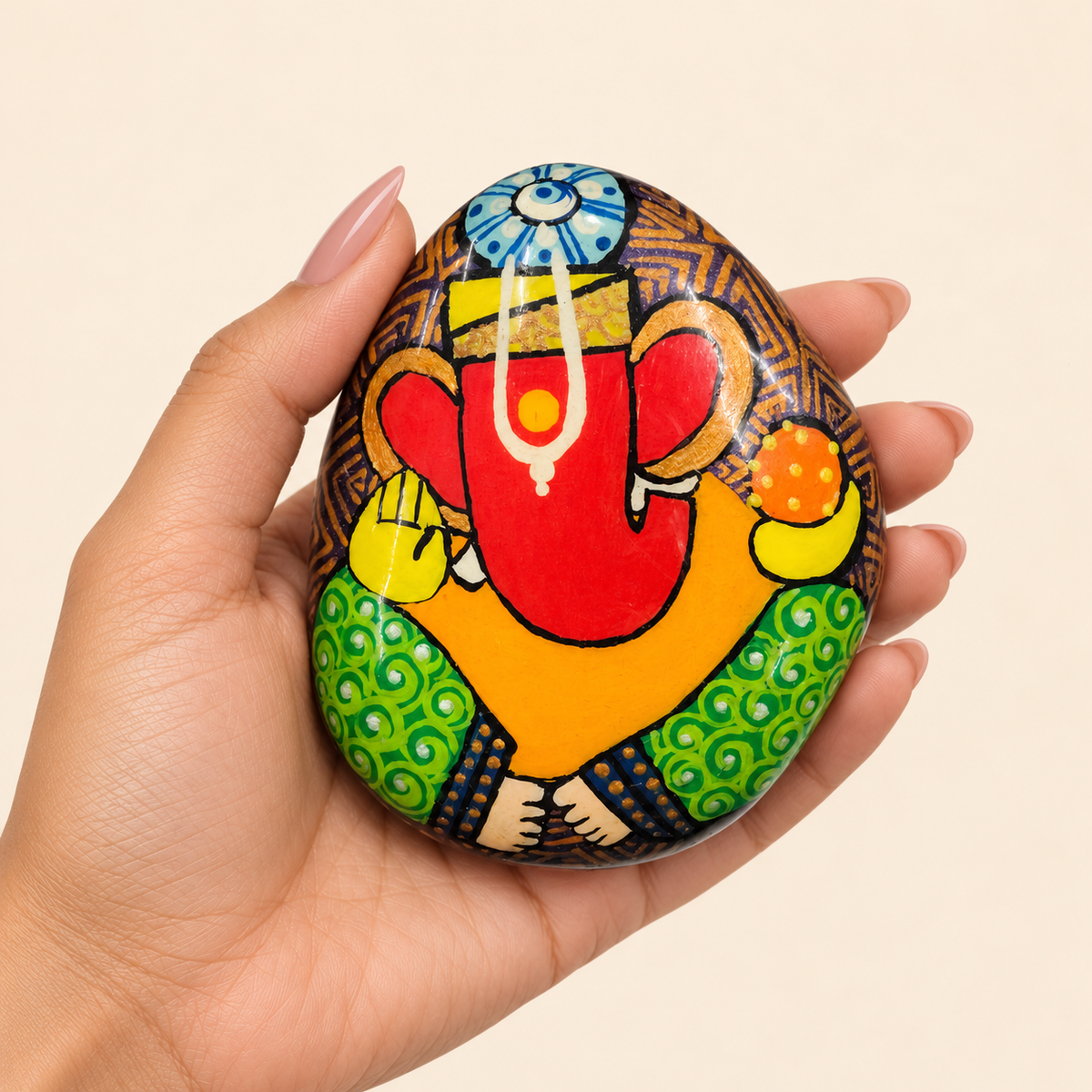 Ganesh: Sunlit Prosperity hand-painted natural pebble art, shown in hand for scale