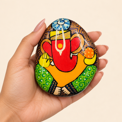 Ganesh: Sunlit Prosperity hand-painted natural pebble art, shown in hand for scale