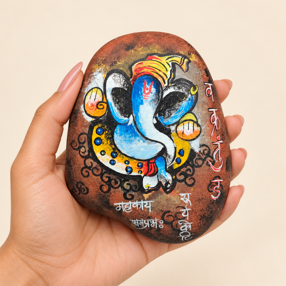 Ganesh: Auspicious Beginning hand-painted natural pebble art, shown in hand for scale