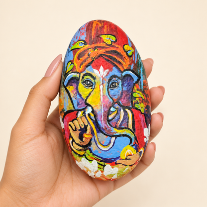 Ganesh: Festival of Colour hand-painted natural pebble art, shown in hand for scale