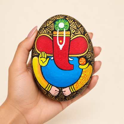 Ganesh: Golden Guardian hand-painted natural pebble art, shown in hand for scale