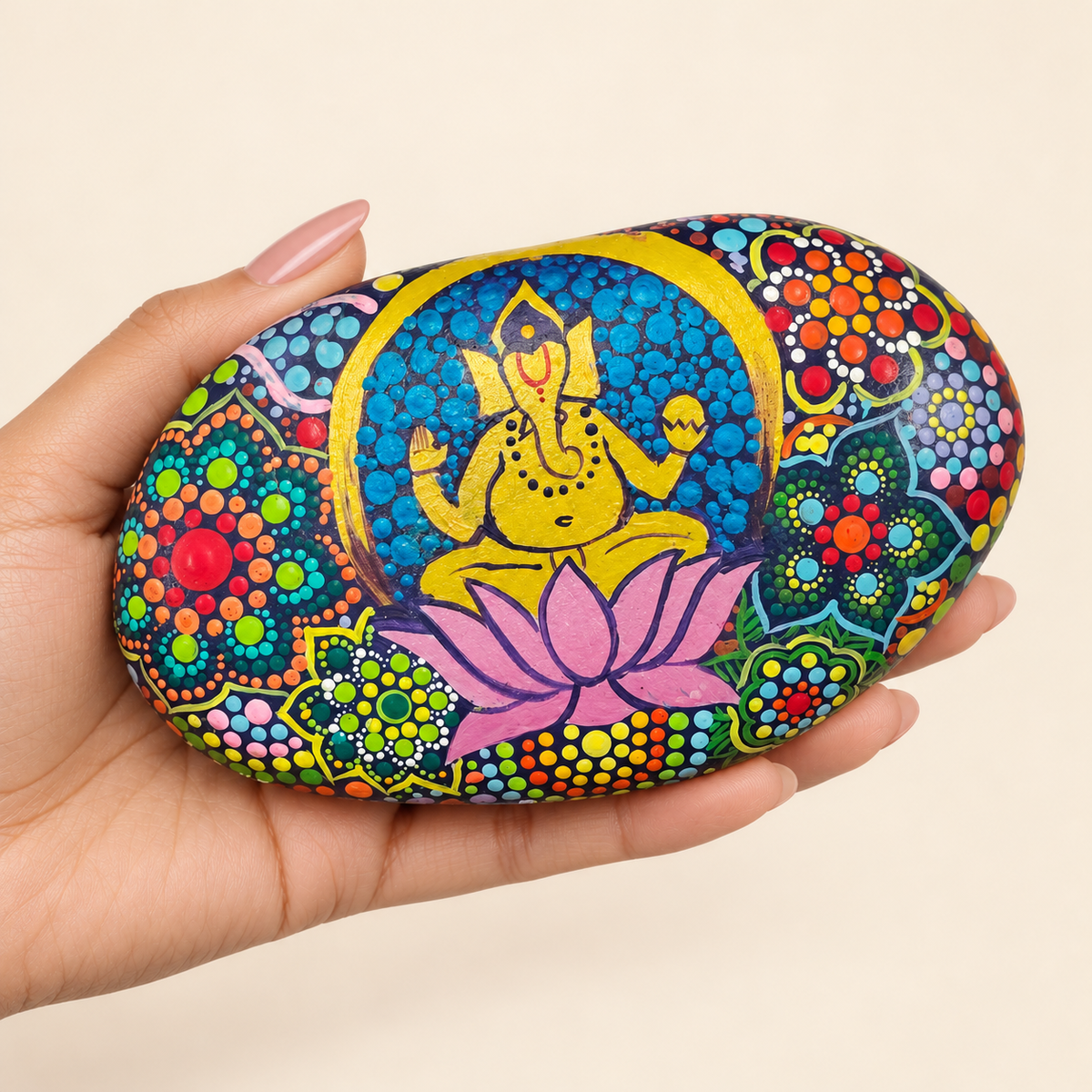 Ganesh: Garden of Abundance hand-painted natural pebble art, shown in hand for scale