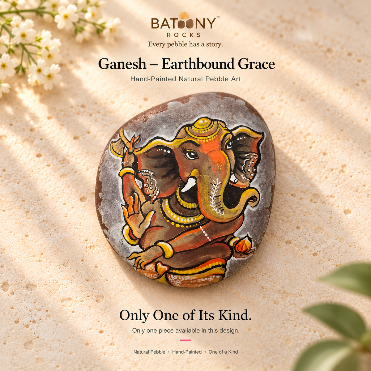 Ganesh: Earthbound Grace hand-painted natural pebble art, on a warm stone surface