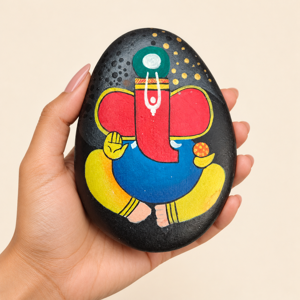 Ganesh: Midnight Blessing hand-painted natural pebble art, shown in hand for scale