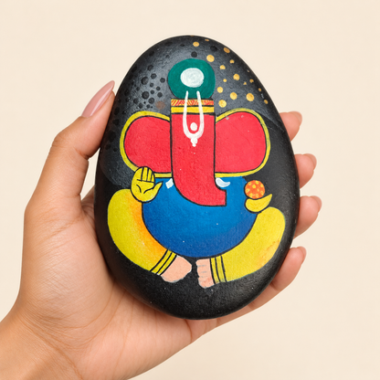 Ganesh: Midnight Blessing hand-painted natural pebble art, shown in hand for scale