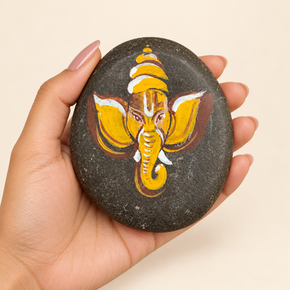 Ganesh: Golden Simplicity hand-painted natural pebble art, shown in hand for scale