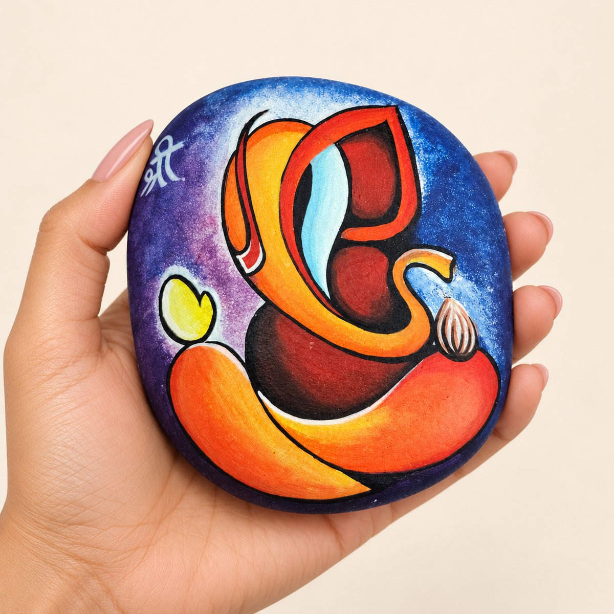 Ganesh: Sunset Harmony hand-painted natural pebble art, shown in hand for scale