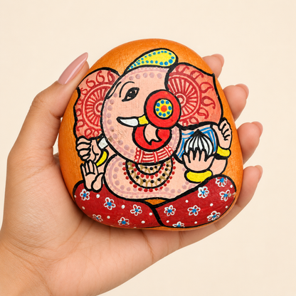 Ganesh: Joyful Marigold hand-painted natural pebble art, shown in hand for scale
