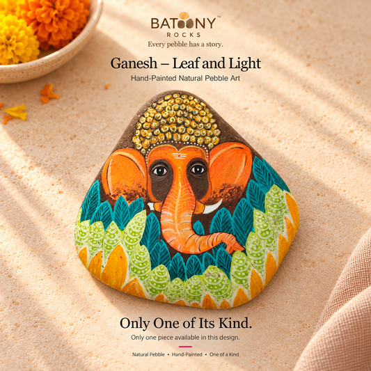 Ganesh: Leaf and Light hand-painted natural pebble art, on a warm stone surface