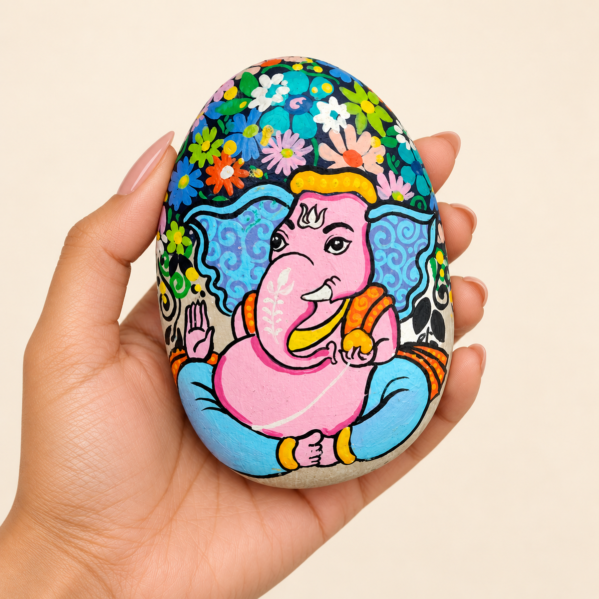 Ganesh: Blossom Blessing hand-painted natural pebble art, shown in hand for scale