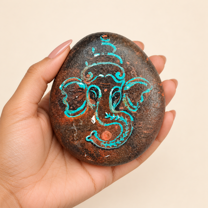Ganesh: Turquoise Whisper hand-painted natural pebble art, shown in hand for scale