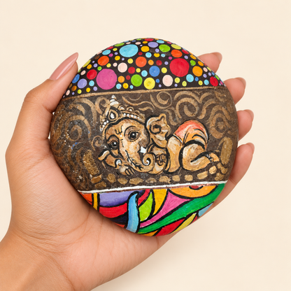 Ganesh: Rainbow Reverie hand-painted natural pebble art, shown in hand for scale