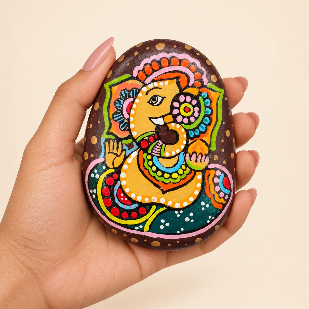Ganesh: Joyful Offering hand-painted natural pebble art, shown in hand for scale