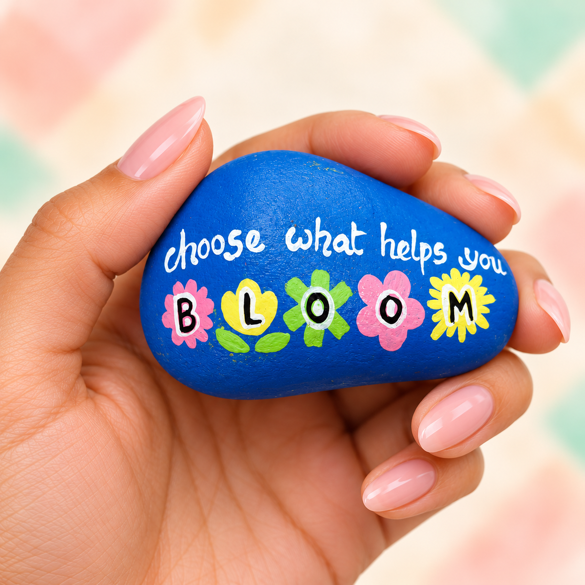 Choose to Bloom: selected hand-painted pebble held in hand