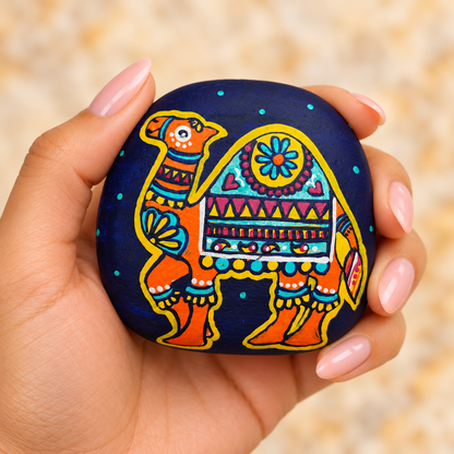 Desert Tales: Peacock and Camel: selected hand-painted pebble held in hand