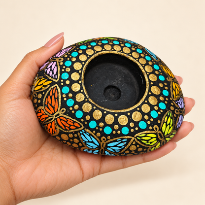 Midnight Mandala: Golden Garden hand-painted natural pebble tealight holder, shown in hand for scale