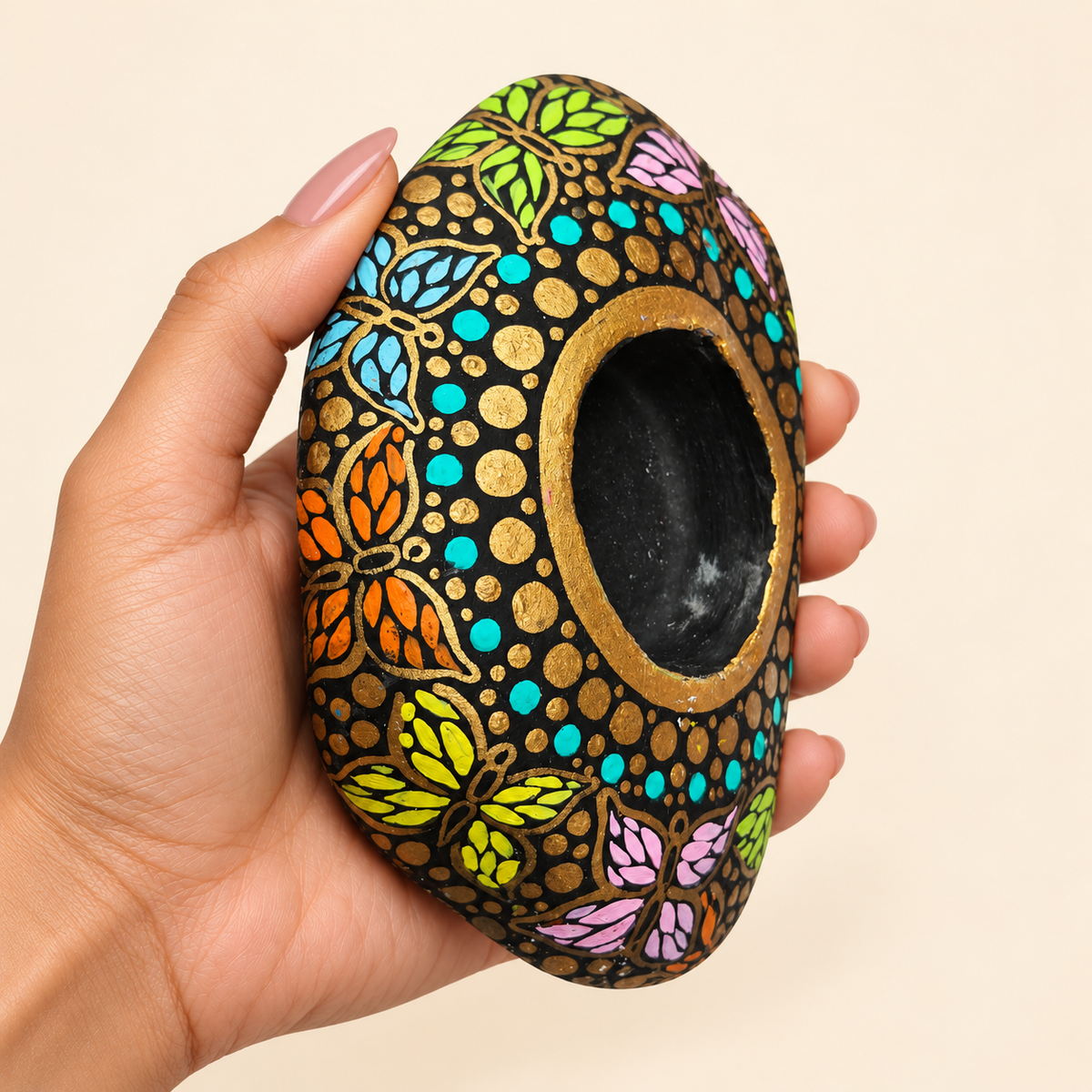 Butterfly Garden: Moonlit Gold hand-painted natural pebble tealight holder, shown in hand for scale