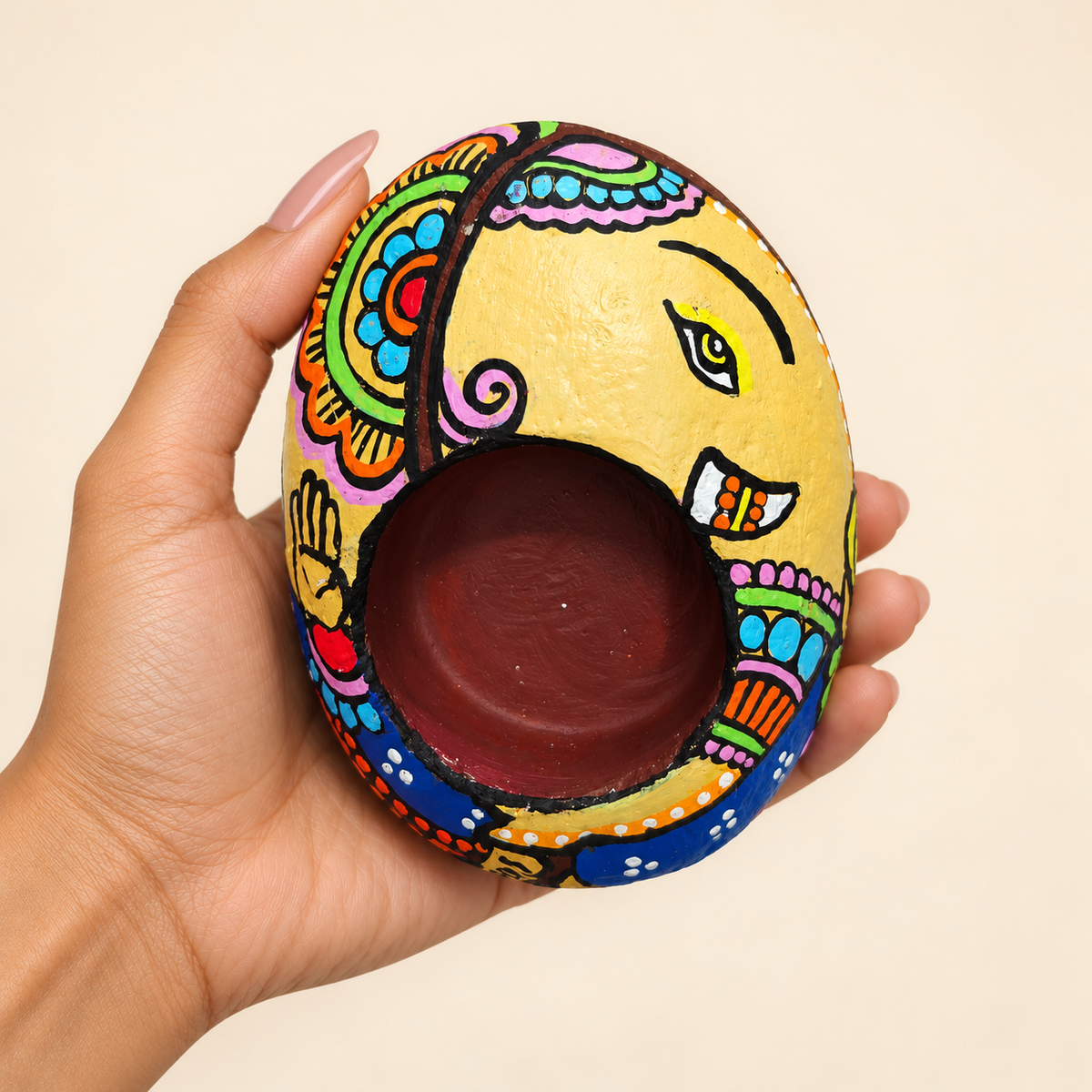 Ganesh: Festive Crescent hand-painted natural pebble tealight holder, shown in hand for scale