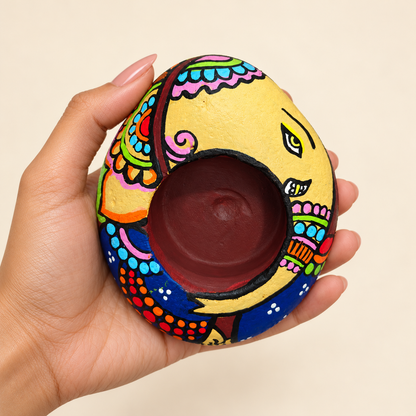 Ganesh: Petal Garland hand-painted natural pebble tealight holder, shown in hand for scale