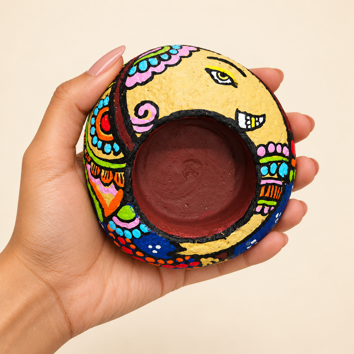 Ganesh: Lotus Garland hand-painted natural pebble tealight holder, shown in hand for scale