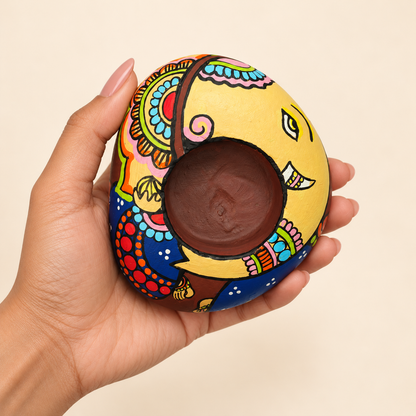 Ganesh: Auspicious Colours hand-painted natural pebble tealight holder, shown in hand for scale