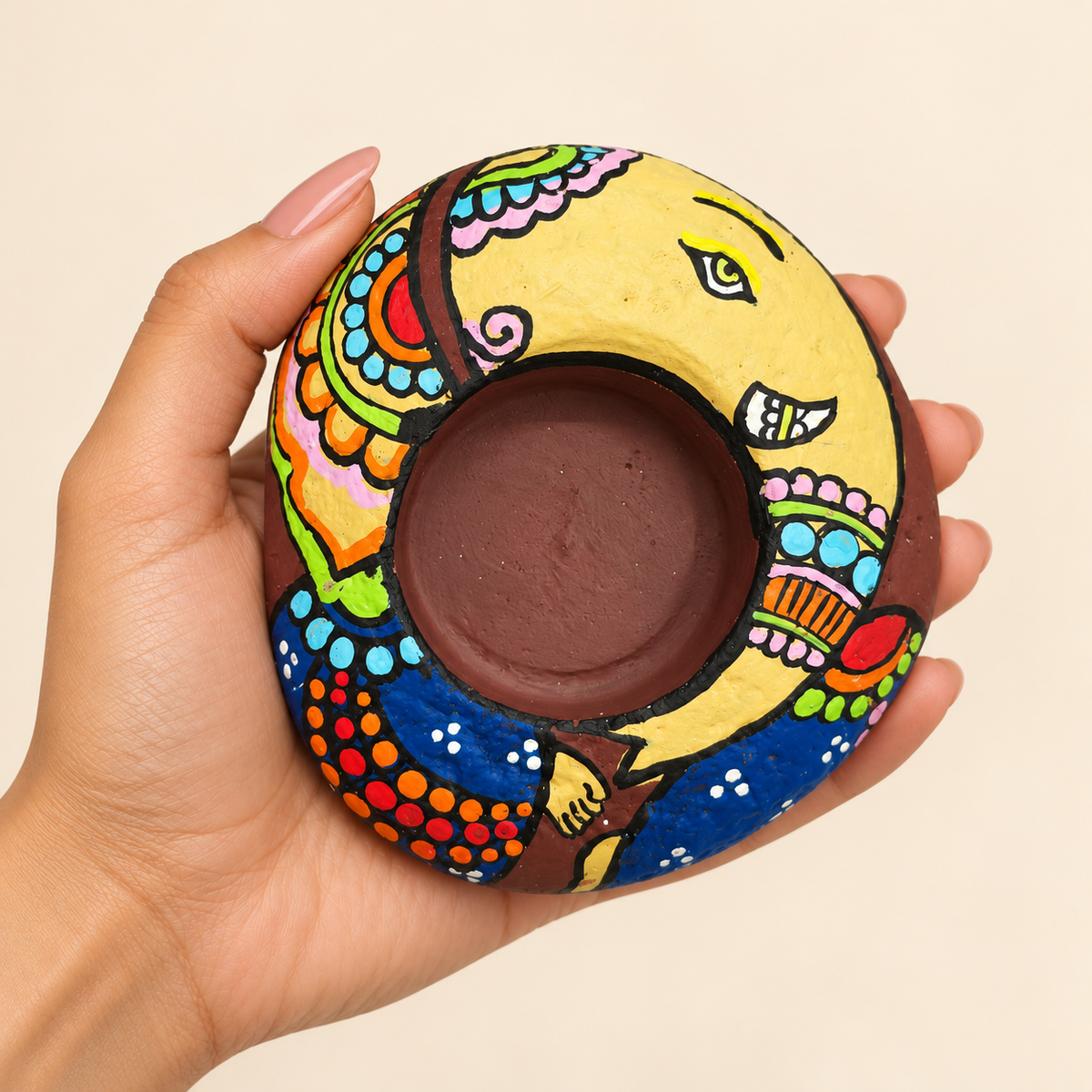 Ganesh: Ceremonial Bloom hand-painted natural pebble tealight holder, shown in hand for scale