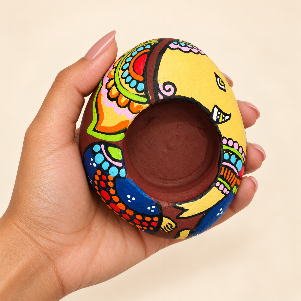 Ganesh: Golden Celebration hand-painted natural pebble tealight holder, shown in hand for scale