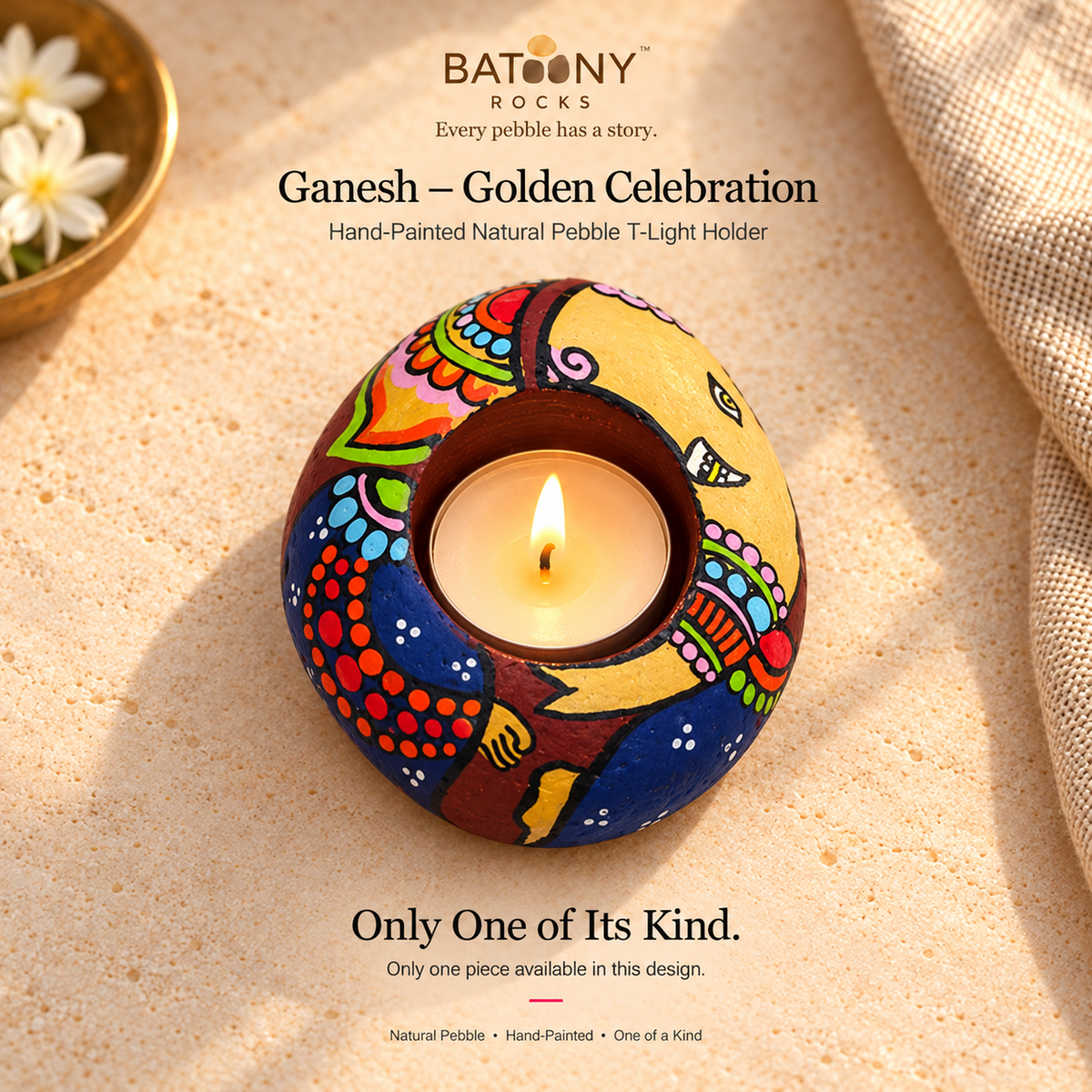 Ganesh: Golden Celebration hand-painted natural pebble tealight holder, on a warm stone surface