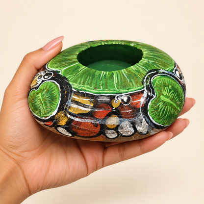 Forest Lotus: Emerald Stillness hand-painted natural pebble tealight holder, shown in hand for scale