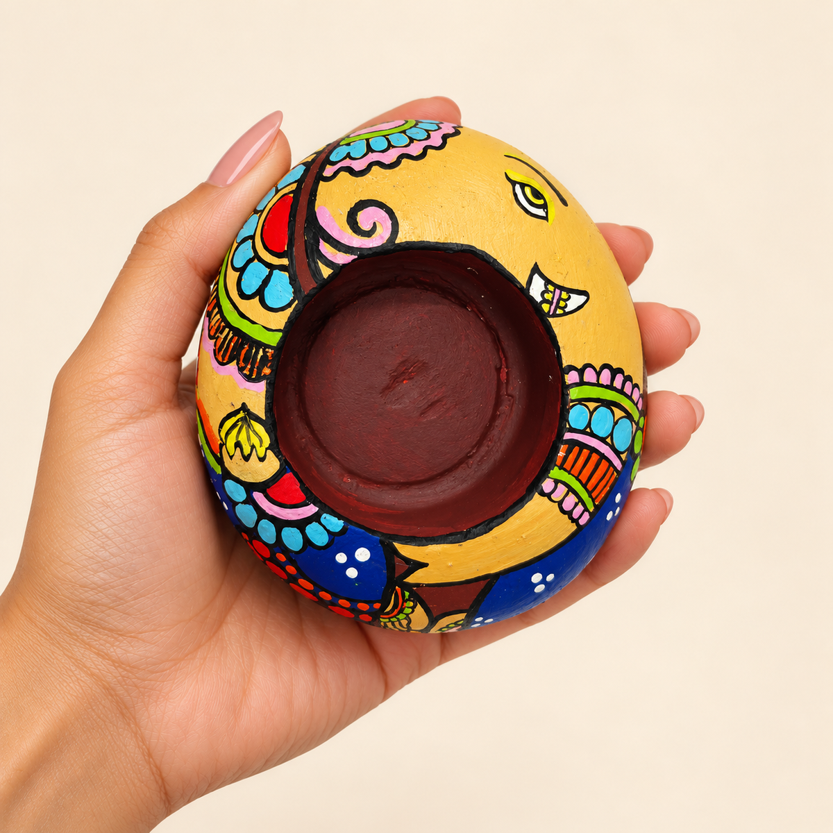 Ganesh: Petal Grace hand-painted natural pebble tealight holder, shown in hand for scale