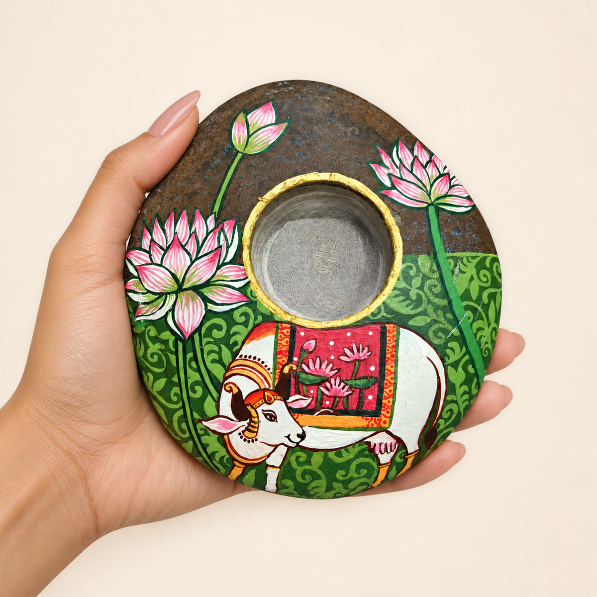 Kamdhenu: The Lotus Blessing hand-painted natural pebble tealight holder, shown in hand for scale