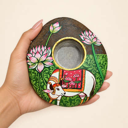Kamdhenu: The Lotus Blessing hand-painted natural pebble tealight holder, shown in hand for scale