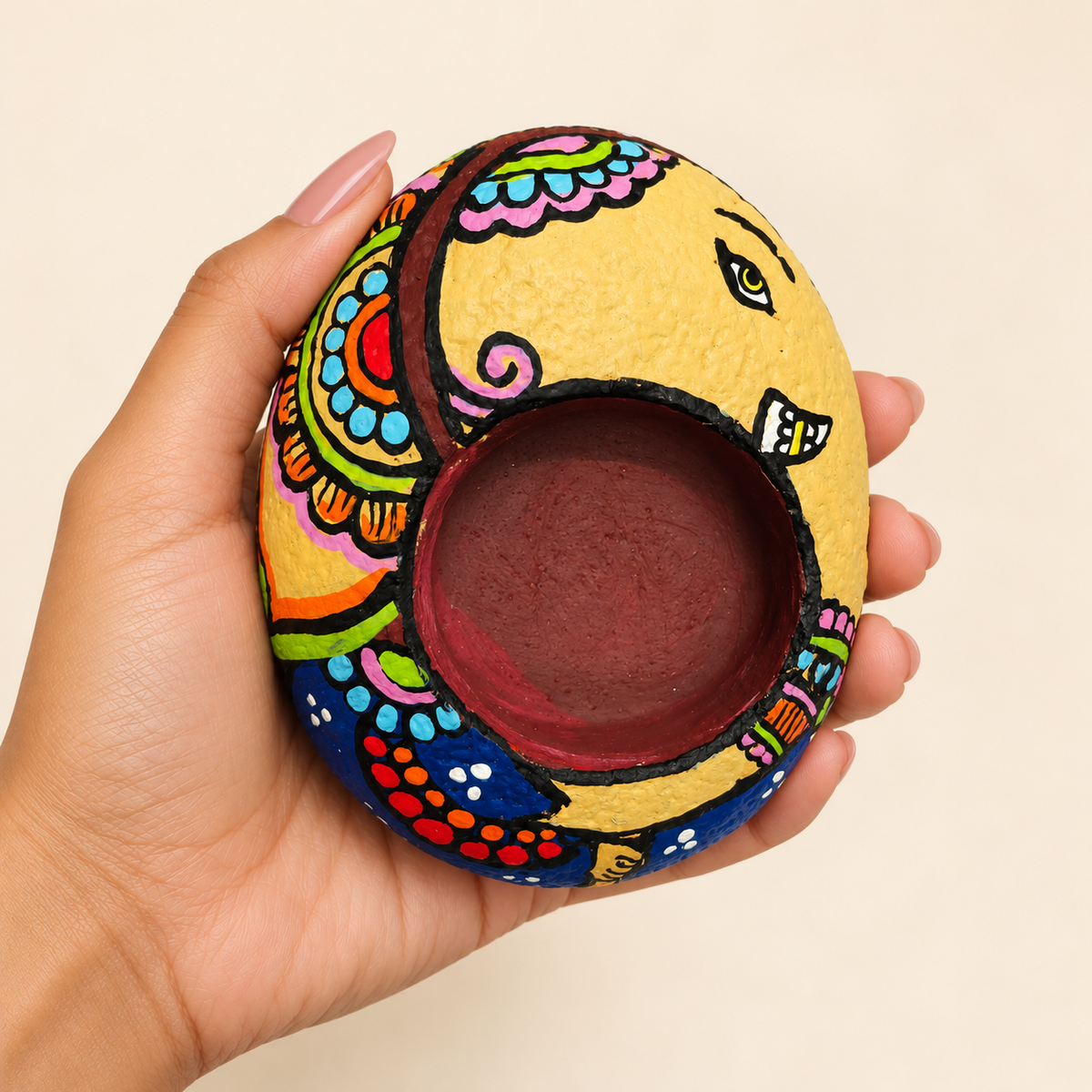 Ganesh: Joyful Bloom hand-painted natural pebble tealight holder, shown in hand for scale